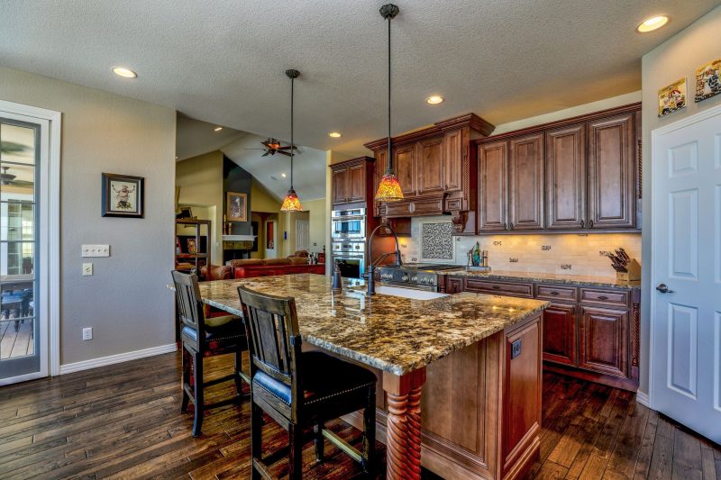 Stylish kitchen with a granite island, wooden cabinets, and modern appliances, showcasing a rustic and contemporary design blend.
